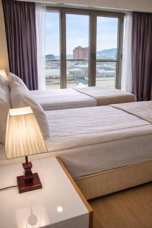 two beds in a hotel room with a window at Diplomat Suites Hotel in Baku