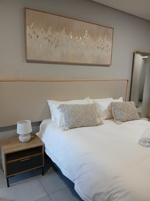 a bedroom with two white beds and a night stand at Kinn Accommodation in Bloemfontein