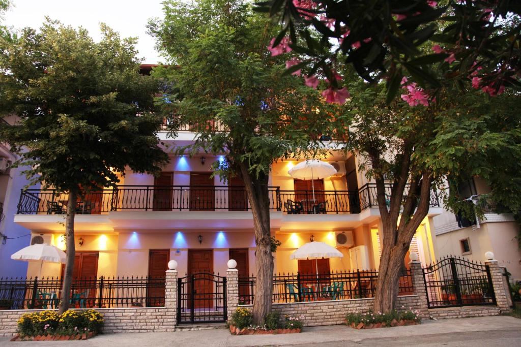 un gran edificio blanco con árboles delante de él en Vasiliki Apartments, en Platamonas