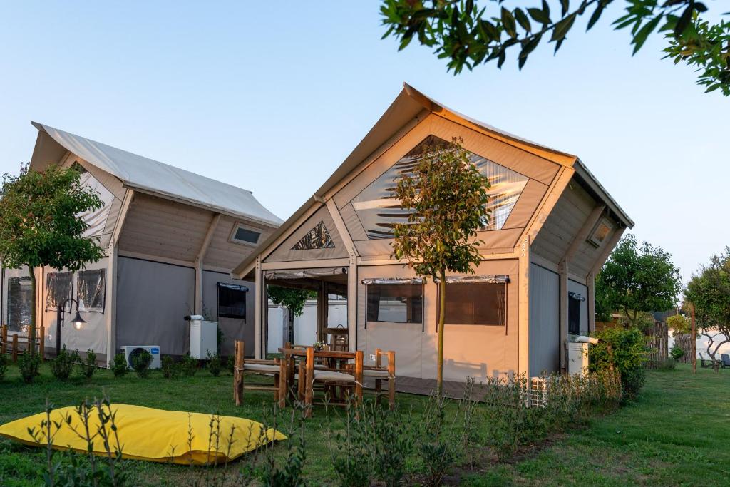 a house with a table and a yellow tent in the yard at Procida Camp & Resort - Ciraccio in Procida