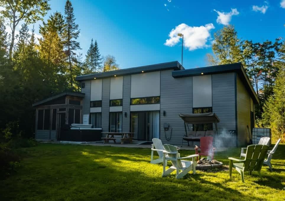 a house with a grill and chairs in the yard at Spa - Lake access - Absolute Comfort - L'Herisson in Chertsey