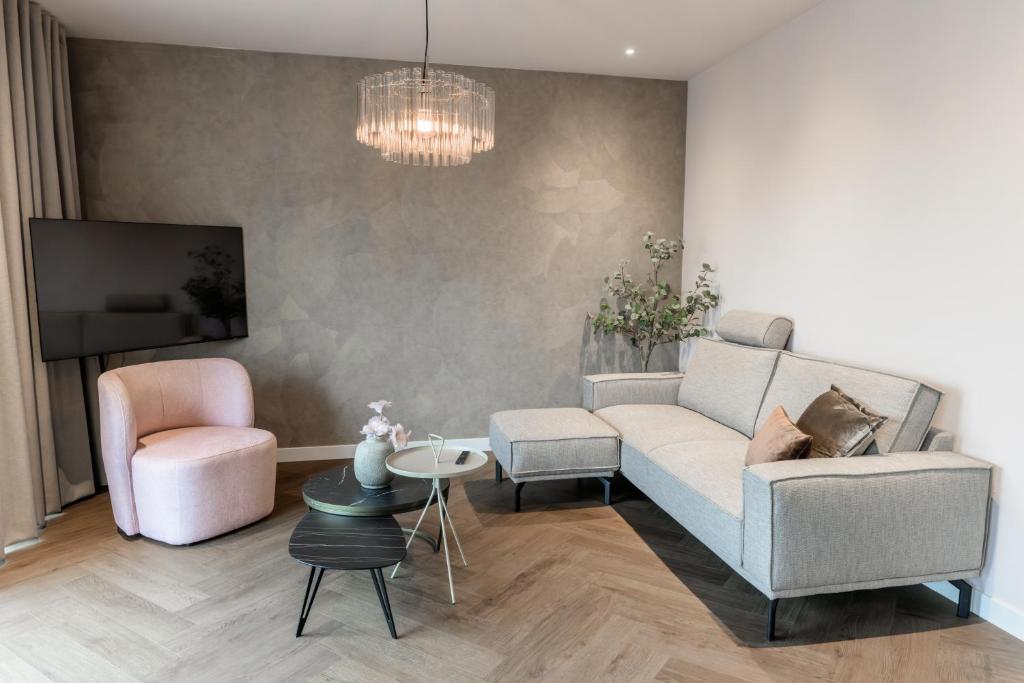 a living room with a couch and a chair and a tv at Slapen bij van O 2 in Yerseke