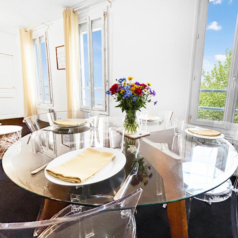 a dining room with a table with chairs and a vase of flowers at Superbe T3 familial et rénové au cœur de la ville - Proche Paris in Alfortville
