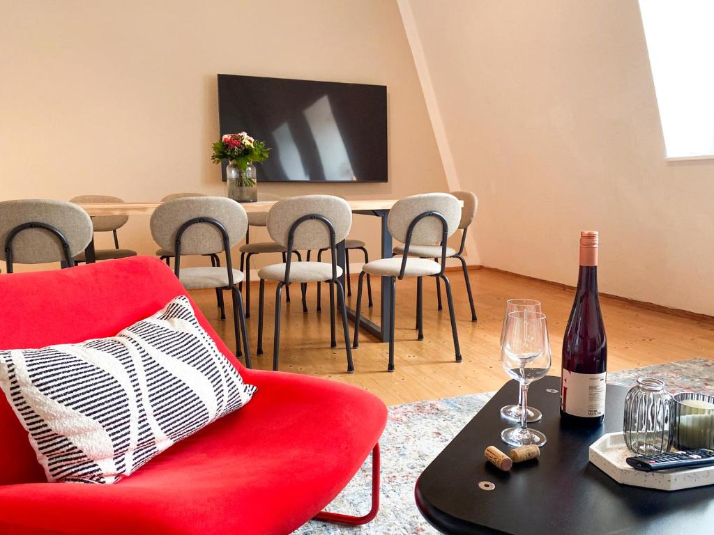 a living room with a red chair and a table at WEINQUARTIER Naumburg 6 Apartments Eventraum Fahrradraum Kaffee Küche Parken in Naumburg