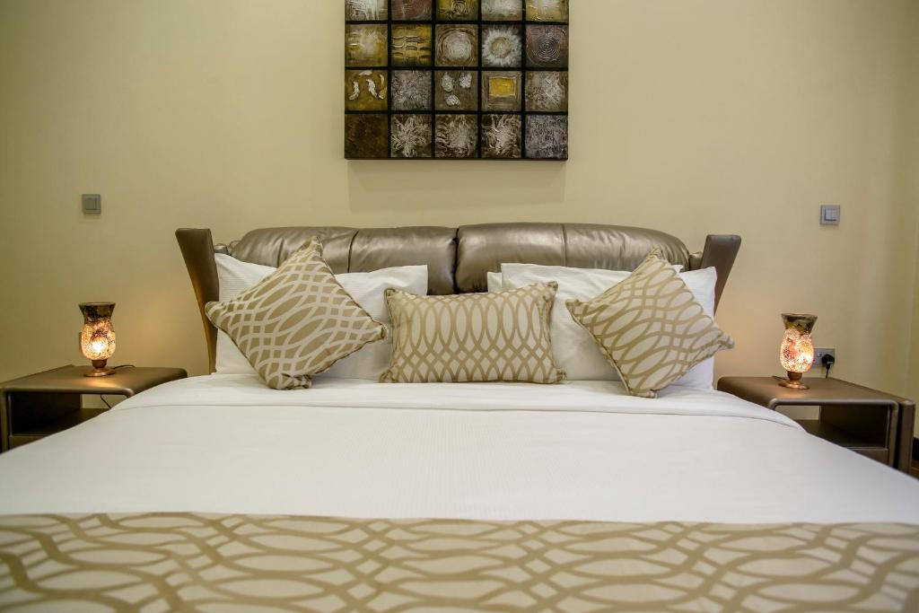 a bedroom with a bed with pillows and two tables at The Landmark Suites in Nairobi