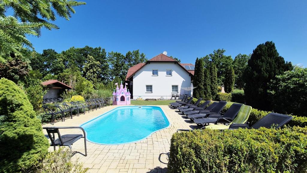 a swimming pool with chairs and a house at Ubytování Mája in Třeboň