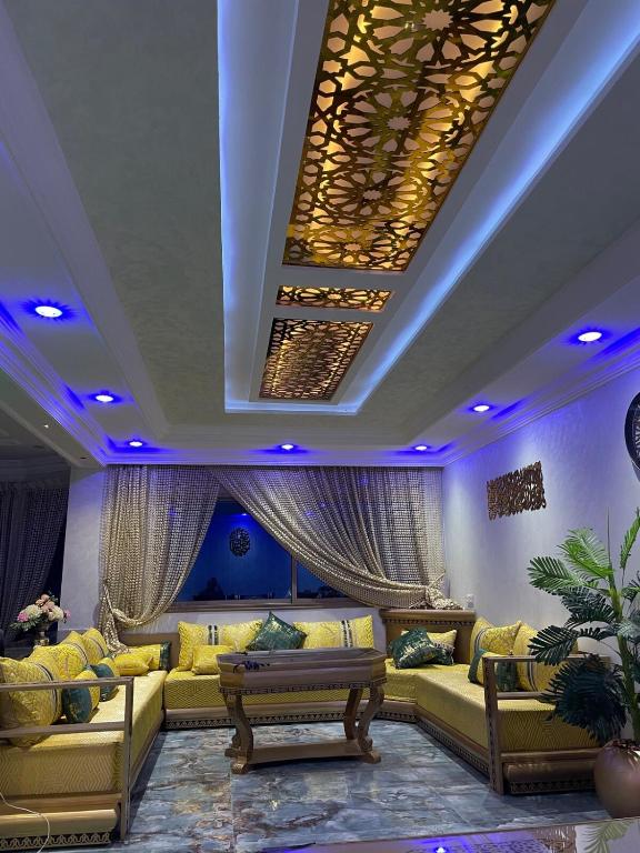 a living room with yellow couches and blue lighting at Villa haut standing vue mere in Kenitra