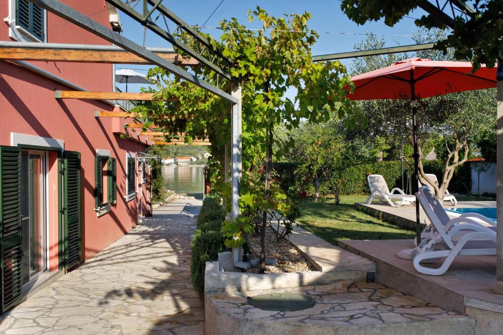 a patio of a house with a pool and an umbrella at Villa Luna in Sutomišćica