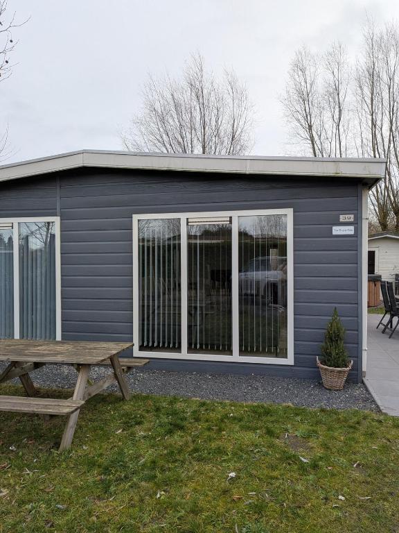 a gray garage with a picnic table and a bench at Bright Holiday Home with Hot Tub Near Breda in Molenschot