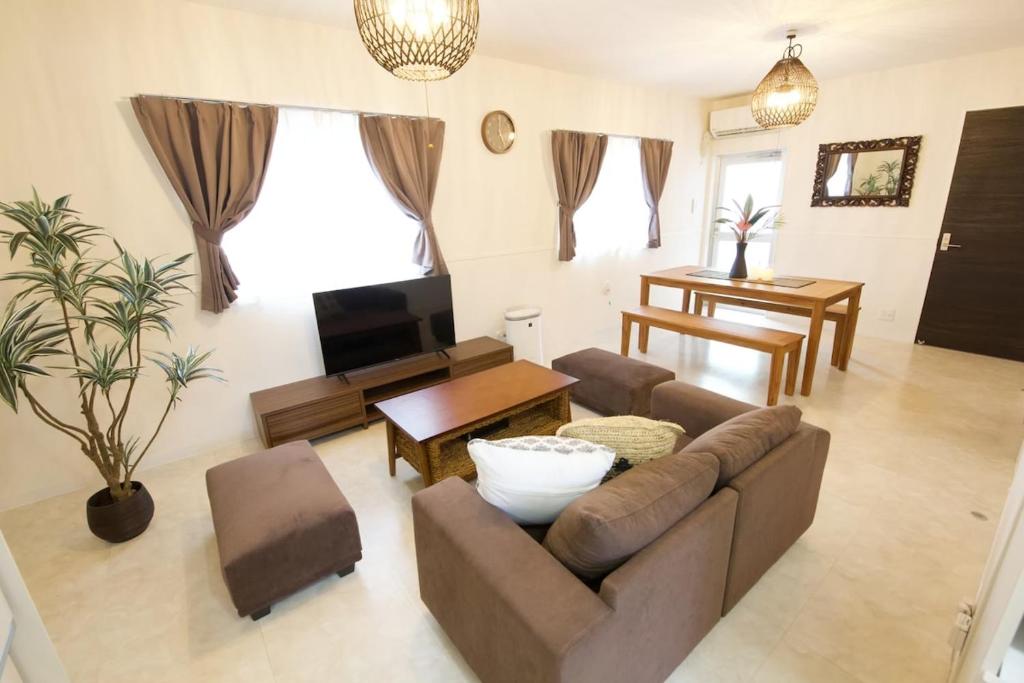 a living room with a couch and a tv at Sunstone GINOWAN 1F in Futemma