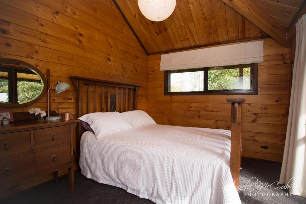 een slaapkamer met een bed in een houten hut bij Frankie & Hugh's in Ohakune