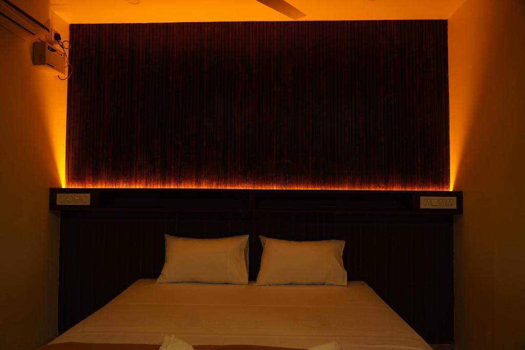 a bed with a black headboard with lights above it at DD COZY INN sntower in Tiruchirappalli