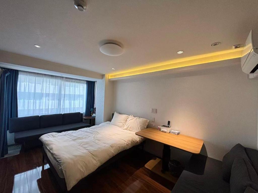 a bedroom with a bed and a table and a couch at Eko House in 横浜石川町駅 in Yokohama