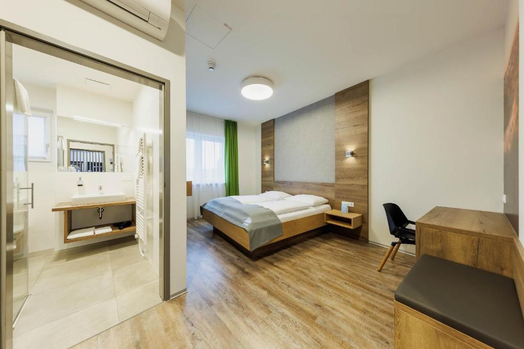 a hotel room with a bed and a bathroom at Das schlaf&GUT - Self Check-In in Leibnitz