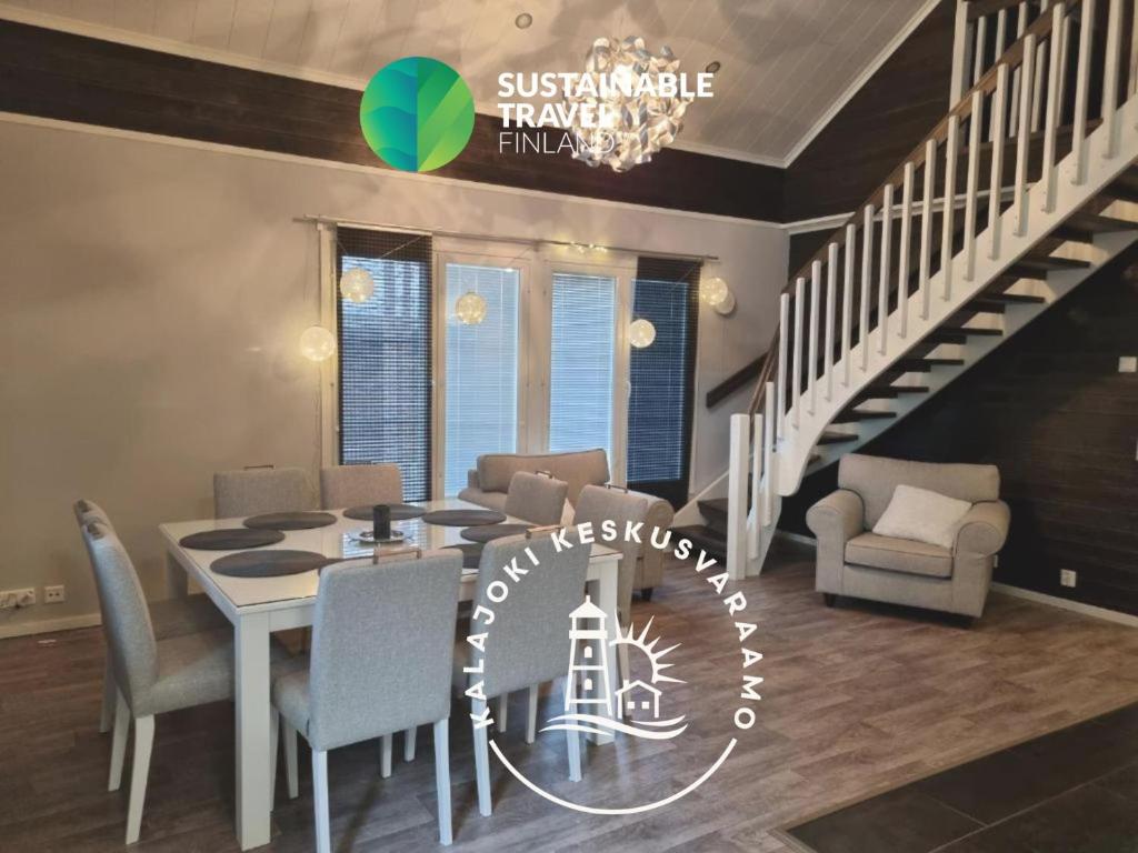 a dining room with a table and chairs and a staircase at Villa Sara in Kalajoki