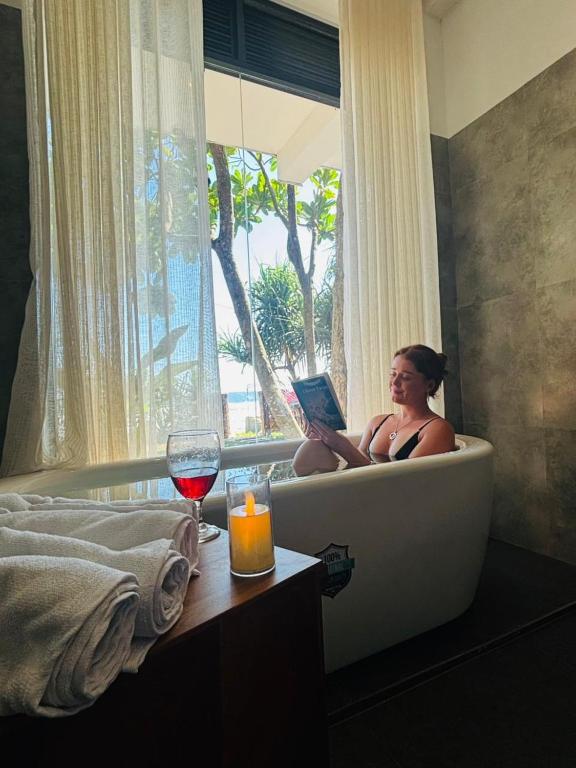 a woman sitting in a bath tub with a laptop at La Brisa By Harry Beach Villa in Dickwella