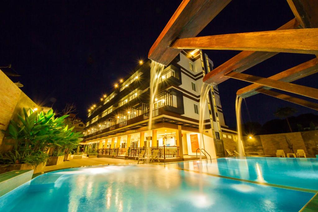 un hotel con piscina por la noche en TH beach hotel, en Hua Hin
