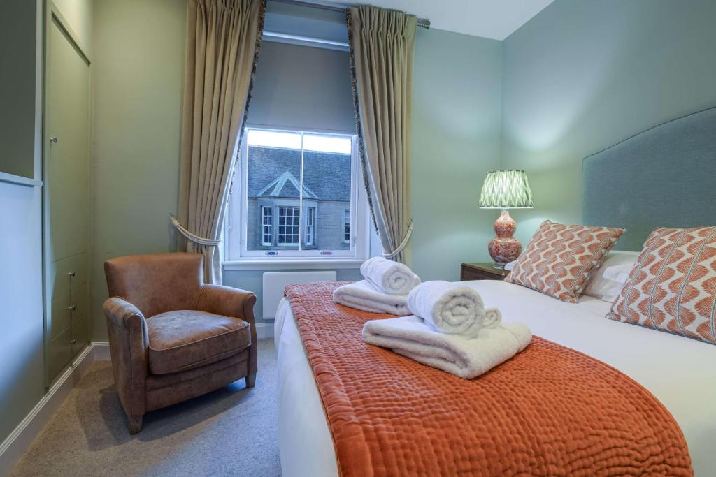 a bedroom with a bed and a chair and a window at 20 Golf Place in St. Andrews