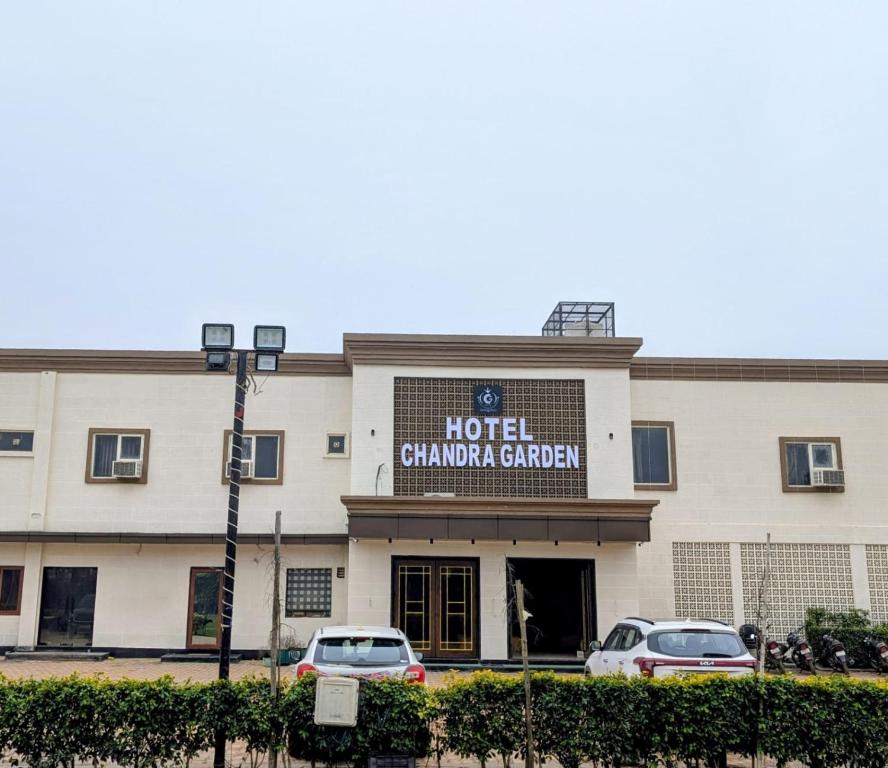a hotel cambridge garden with cars parked in front of it at HOTEL chandra garden in Govardhan