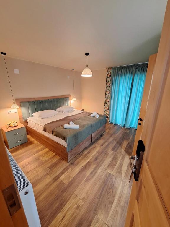 a bedroom with a large bed and blue curtains at Hotel-restaurant Stumari in Ushguli