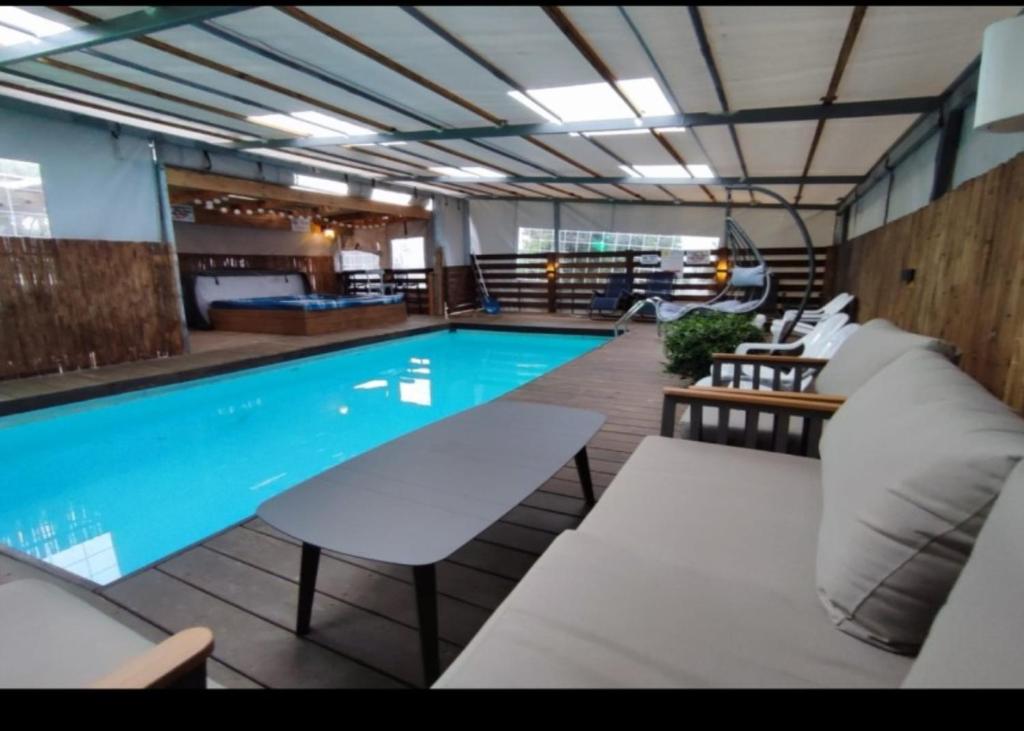 a large swimming pool with chairs and a couch at קסם הרימון - 4 צימרים מושלמים עם בריכה וג'קוזי in ‘Azriqam