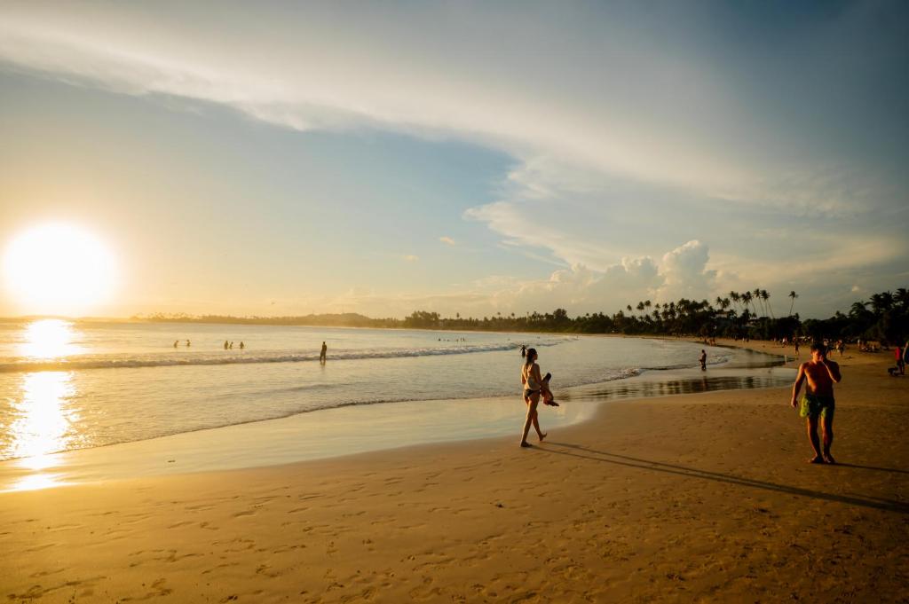 two people walking on the beach at sunset at Enu Homestay in Dickwella