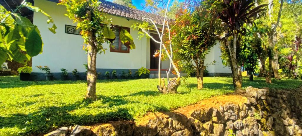 a house with trees and a stone wall at Verdant Vagamon Farm House in Vagamon