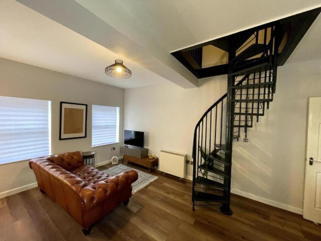 a living room with a couch and a spiral staircase at Central Industrial Chic 2-Bedroom Flat in Crewe