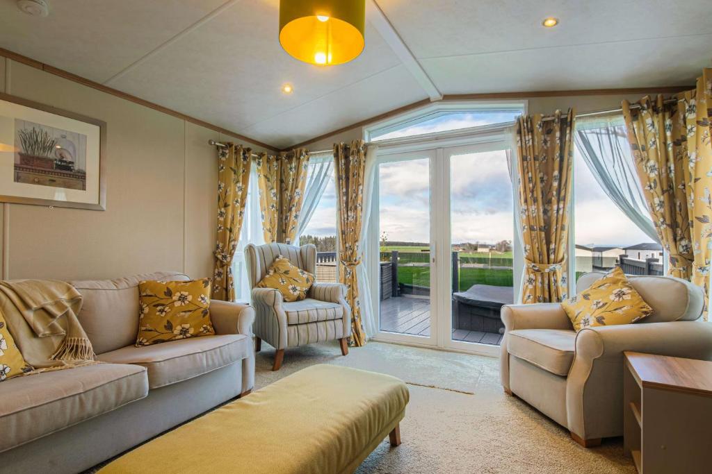 a living room with couches and a large window at Hot Tub Lodge 31 Cameron, St Andrews in St. Andrews