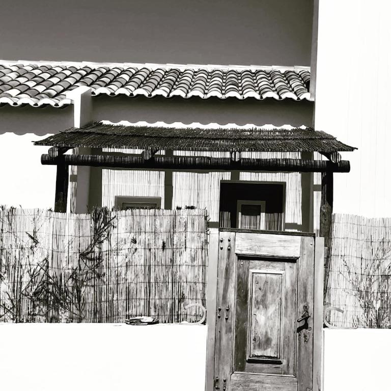 a building with a wooden door and a fence at Pego Beach House in Grândola