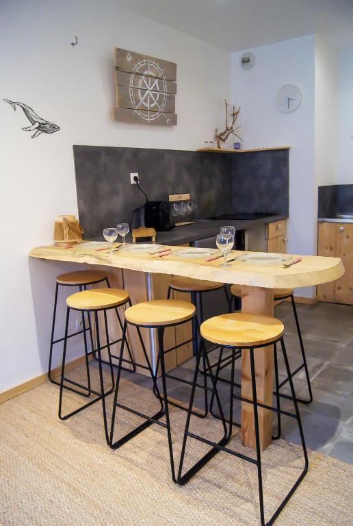 a kitchen with a table and stools with wine glasses on it at Le Havre Familial - 5 couchages climatisé in Romans-sur-Isère