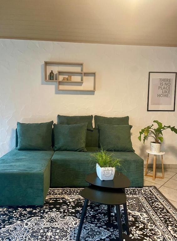 a living room with a green couch and a table at Gartenblick in Blankenheim
