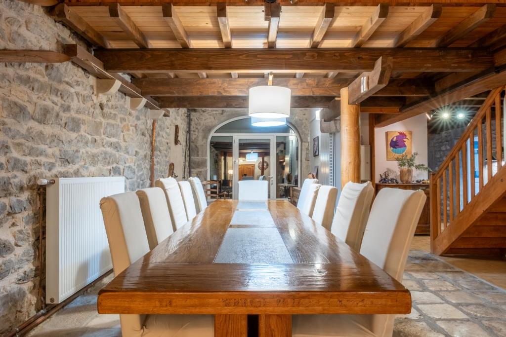 a dining room with a wooden table and white chairs at Gite les fans in Prénovel