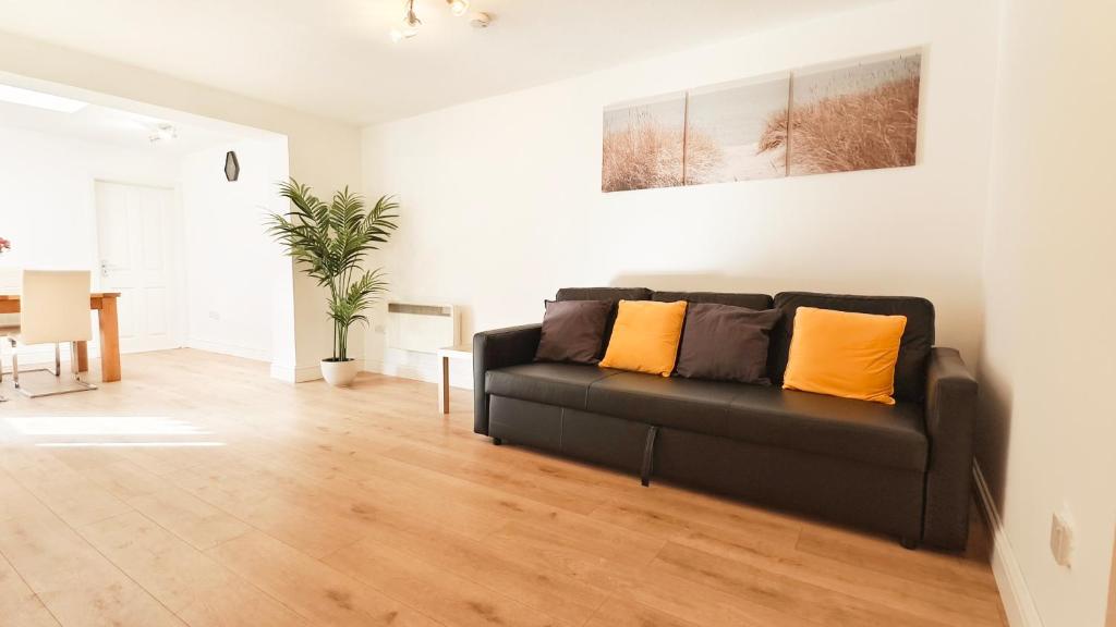 a living room with a black couch with orange pillows at Colindale 4 bedroom house with garden and 2 parking spaces in Colindale