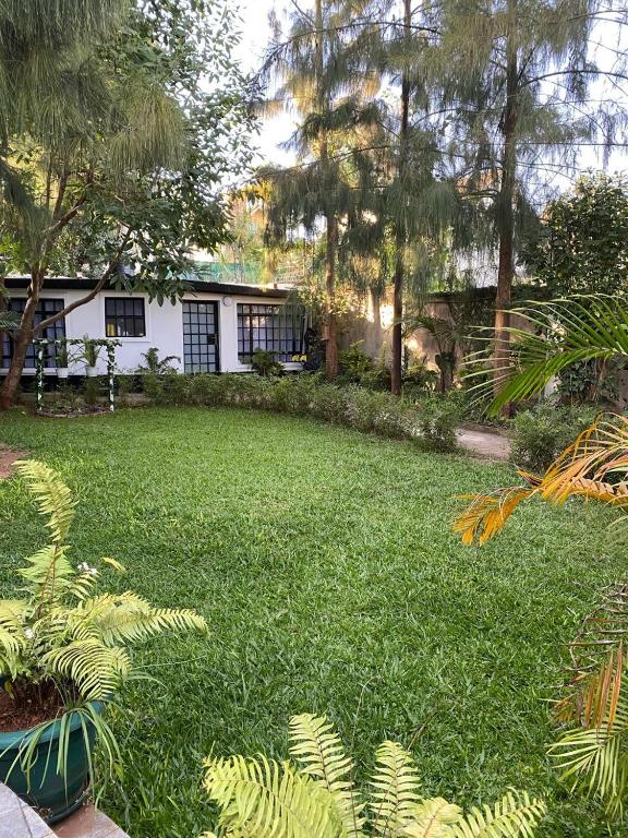 a yard with green grass and trees and a house at Private 2BR Bungalow in Quiet Green Gated Estate in Nairobi