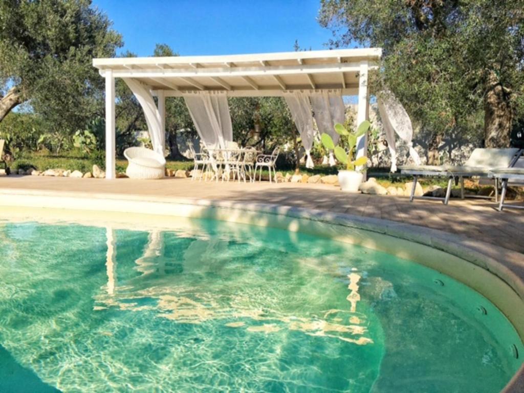 a swimming pool with a pergola and a table and chairs at Villa Dina in Nardò