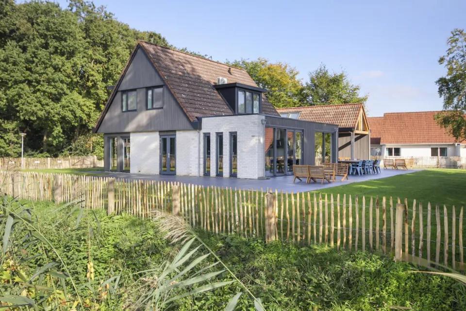 a large white house with a wooden fence at Villa Vechtrijk | 12 persons in Gramsbergen