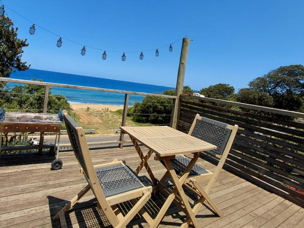 a wooden table and two chairs on a deck with the beach at uMkhaKhaya Container Home in Westbrook