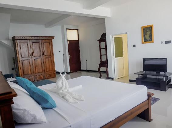 a large white bed in a room with a television at Ocean River View in Ambalangoda