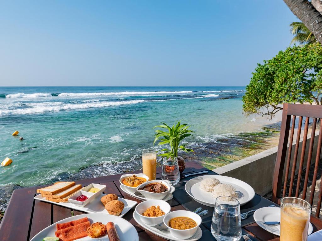 a table with food and the ocean in the background at Florain Otium Talpe in Unawatuna