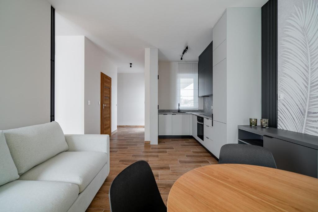a living room with a white couch and a wooden table at Apartamenty Szelągowskiej in Raszyn