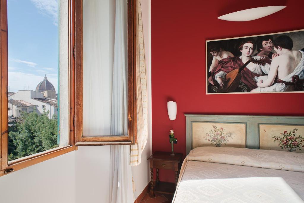 a bedroom with a red wall with a bed and a window at Hotel Caravaggio in Florence