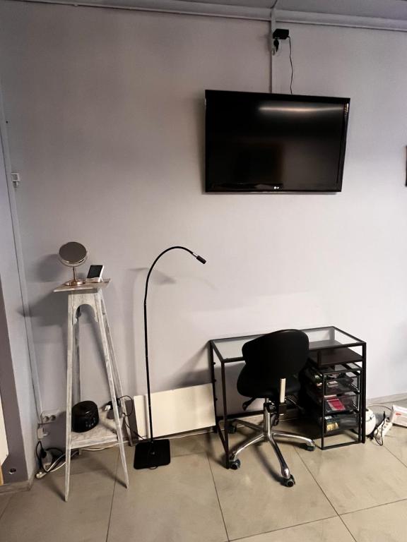 a room with a chair and a television on a wall at Royal Velvet Studio in Kristiansand
