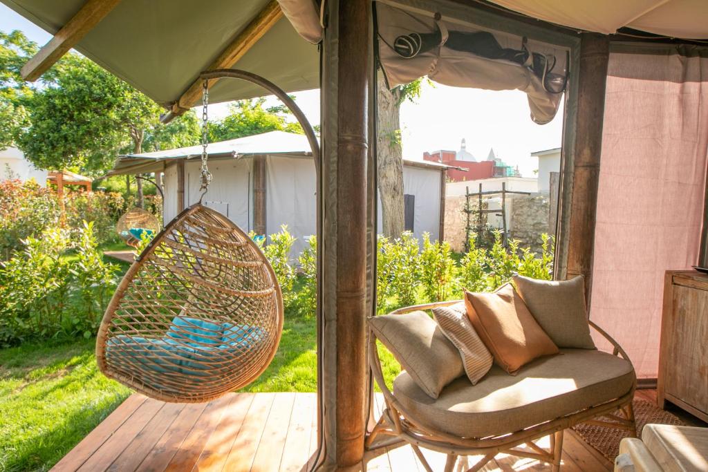 a porch with a swing and a chair on a deck at Procida Camp & Resort - La Caravella in Procida
