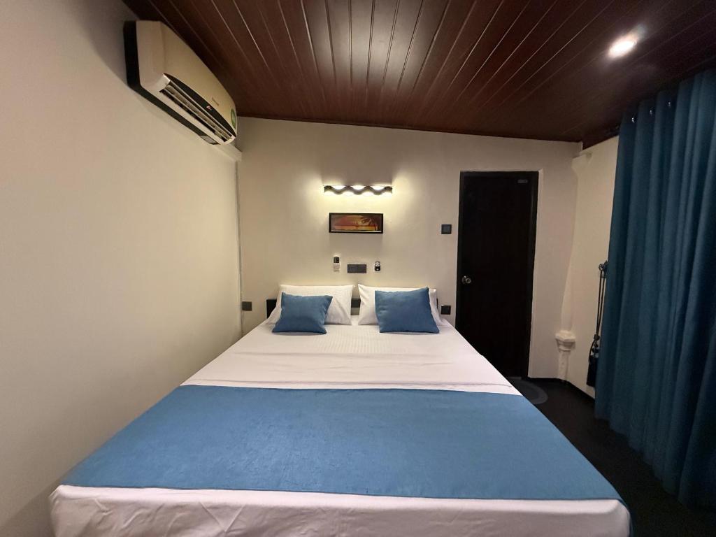 a bedroom with a large bed with blue pillows at Sigiriya Lantern Homestay in Sigiriya