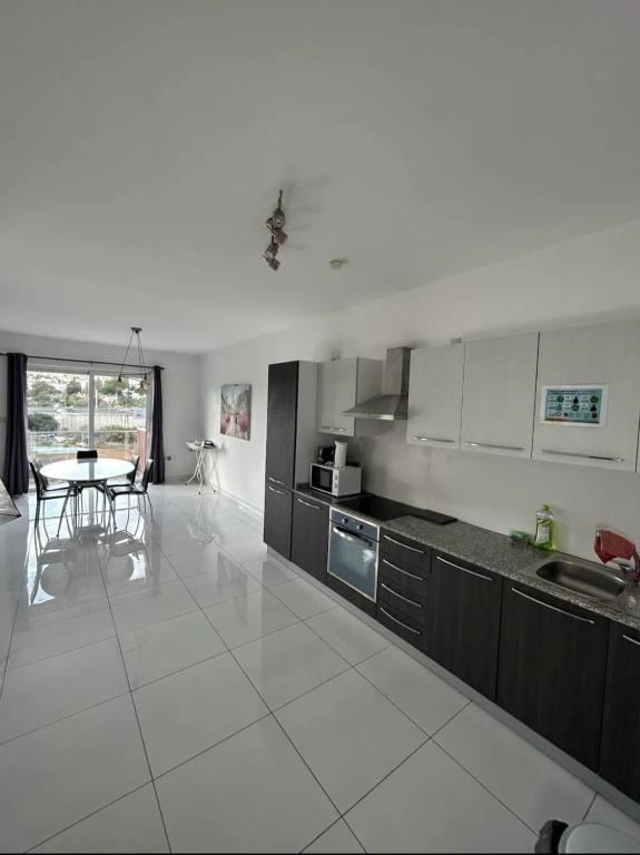 a large white kitchen with a table and a counter at Park Lane Experience Apartments in Il-Gżira