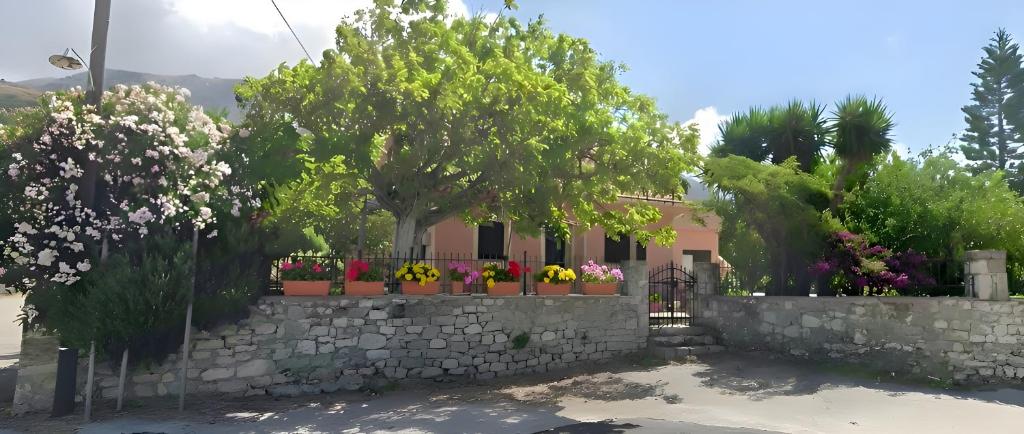 a house with flowers in pots on a stone wall at The Kefalonian Divarata House in Kefalonia