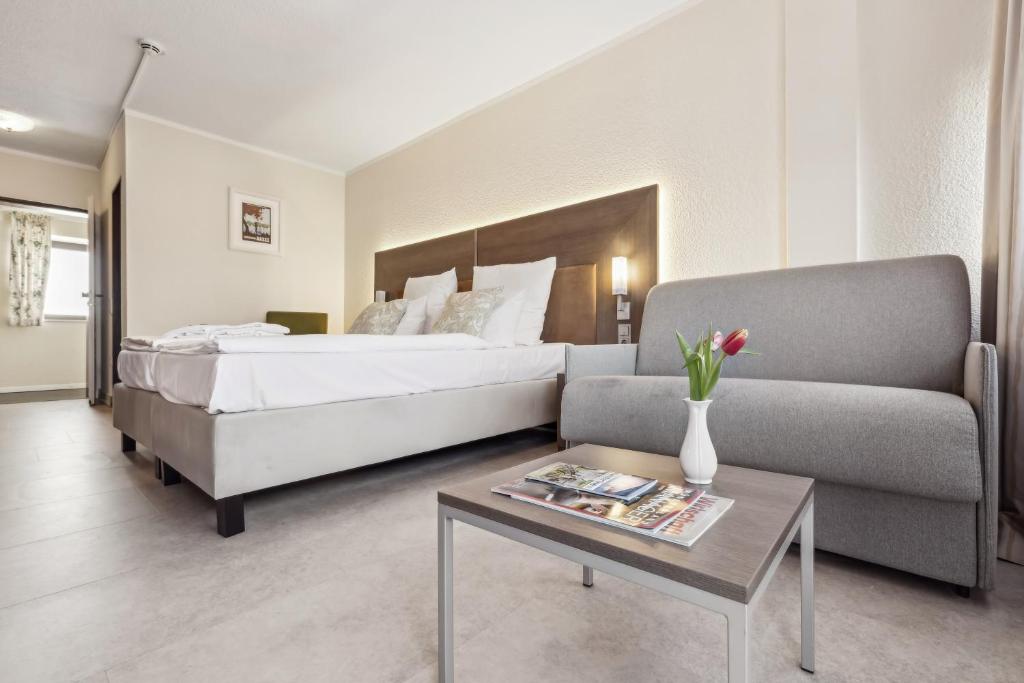 a bedroom with a bed and a couch and a table at Cityhotel Amadeus - 3 Sterne Superior in Münster