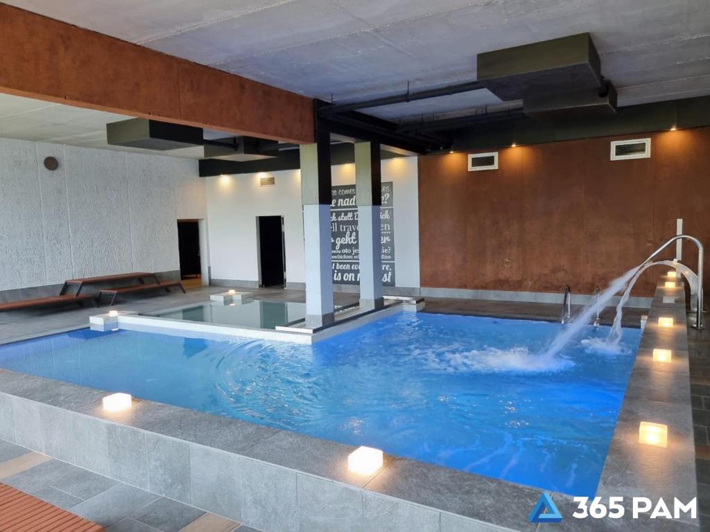a large swimming pool with a water fountain at 365PAM - Apartament nr 32 w Mielenku - BASEN KRYTY, ANIMACJE DLA DZIECI, JACUZZI, SAUNA,PLAC ZABAW W CENIE in Mielenko