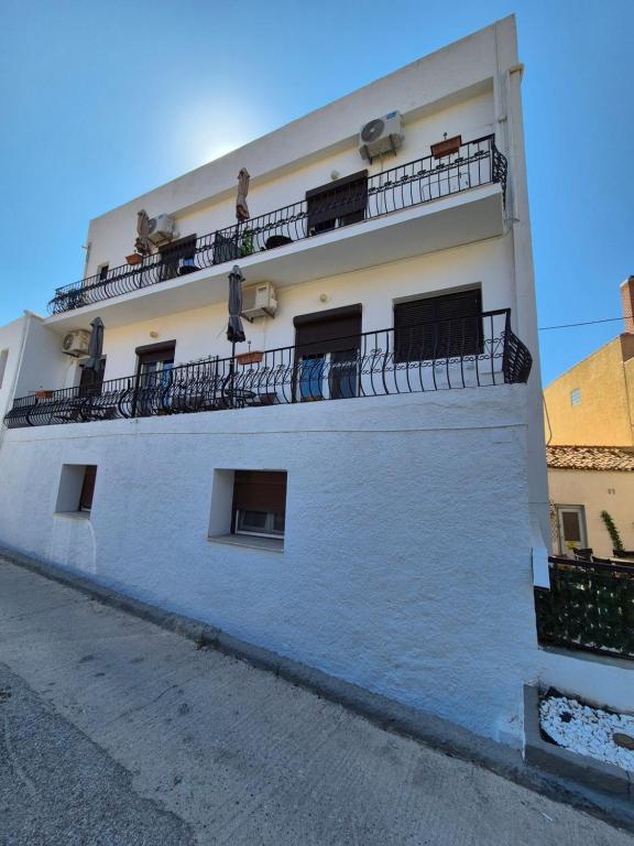 a white building with balconies on top of it at Kostas Studios Apartments - Ενοικιαζόμενα δωμάτια με κουζινάκι in Myrina